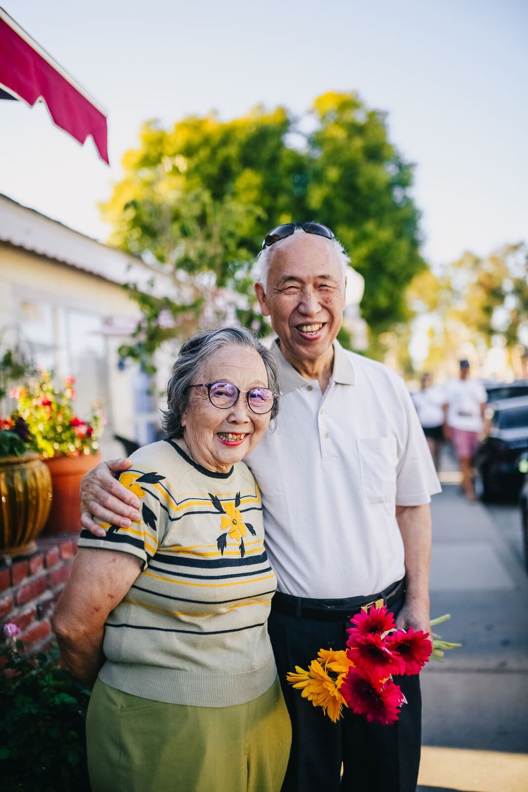 Happy older couple holding flowers on a sunny street